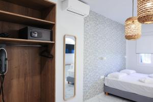a small bedroom with a bed and a mirror at Uphill Unique Boutique Suites in Skiathos Town