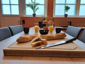 una mesa con pan en una tabla de cortar con un cuchillo en Ospaloft, meublé haut de gamme avec spa privatif, en Arras 3 fotos más