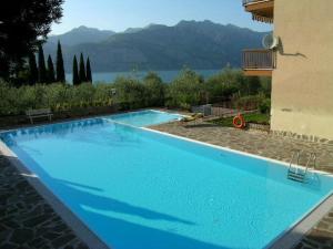 a large blue swimming pool next to a building at 3 rooms apartment whit balcony and lake wiew in Malcesine