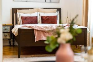 een slaapkamer met een bed met een houten hoofdeinde en kussens bij The- POINT- 3BR Bright Cloud in Boekarest