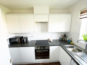 a kitchen with white cabinets and a sink at Gracenote Properties Hemel Hempstead - serviced apartment with FREE parking in Hemel Hempstead