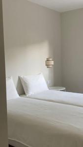 a white bed with white sheets and pillows on it at Casa com jardim perto da praia in Sesimbra