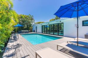 una piscina con sillas y una sombrilla junto a una casa en Heated Pool Modern 5 Bedrooms House 10 minutes to the Ocean, en Miami