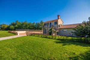 a house with a grassy yard and a pathway at Gorgeous Pool Villa with a fenced garden in Žminj