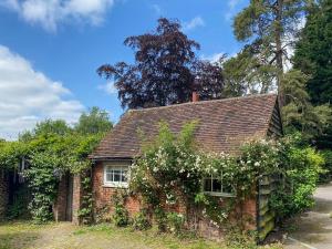 a small brick house with white flowers on it at Old Rectory Cottage in Fernhurst