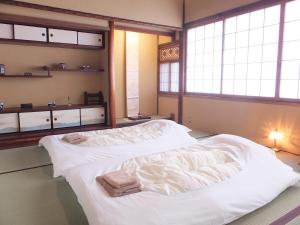 two large beds in a room with windows at Guest House Bokuyado in Kyoto
