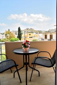 een tafel op een balkon met 2 stoelen en bloemen bij ADONIOS APARTMENTS in Archangelos