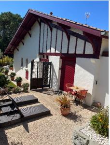een klein wit huis met een rode deur en een tafel bij Le 7 in Capbreton