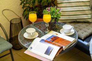 een tafel met een boek en twee glazen sinaasappelsap bij The- POINT- 3BR Bright Cloud in Boekarest