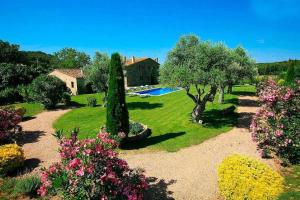 einen Garten mit Bäumen und einem Haus und einem Pool in der Unterkunft Mas dels Avis Tipica Masia Catalana in Vall-llobrega