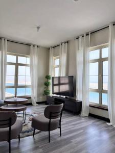 a living room with a tv and chairs and windows at Nazeel - Sea view Marina Apt in King Abdullah Economic City