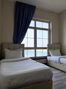 a bedroom with two beds and a large window at Nazeel - Sea view Marina Apt in King Abdullah Economic City