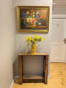 un jarrón de flores en una mesa de madera con una pintura en Mimoza Guesthouse, en Estambul