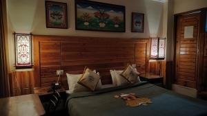 ein Schlafzimmer mit einem Bett mit einem Kopfteil aus Holz in der Unterkunft Auspiscious Him View Hotel in McLeod Ganj