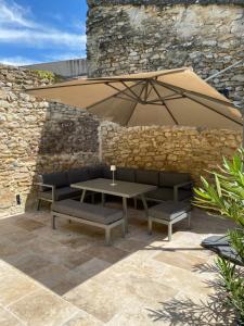 a patio with a table and two benches and an umbrella at La Romance de Grignan in Grignan
