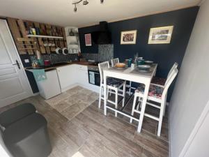 a small kitchen with a white table and chairs at Le Douillet - The Snug in Exideuil
