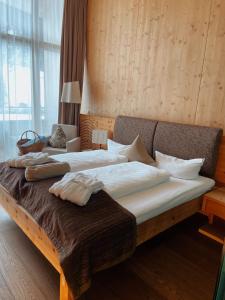 a large bed in a room with a large window at Spa Hotel Zedern Klang in Hopfgarten in Defereggen