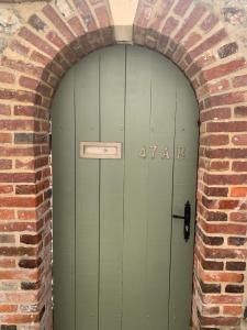 an archway with a green door in a brick wall at Honfleur effet mer 2 in Honfleur