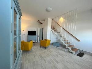 een woonkamer met 2 gele stoelen en een trap bij Brand new 3-level sea view apartment near beach in Il-Pergla