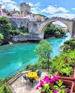 uma mesa e cadeiras junto a um rio com uma ponte em Mostar Delight - Next to Riverside em Mostar