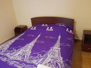 a bed with a purple blanket with the eiffel tower at Casa Dan in Tuzla