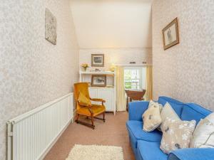 a living room with a blue couch and a chair at The Cottage in Slickly