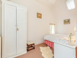 a white bedroom with a bed and a table at The Cottage in Slickly