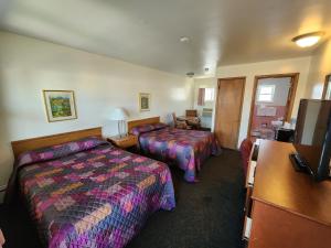 a hotel room with two beds and a desk at Riviera Motel in Erie