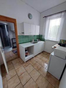 a kitchen with white cabinets and a tile floor at Penzion U Radnice in Doksy