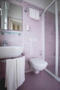 un bagno rosa con lavandino e servizi igienici di Hotel Ronchi a Cervia