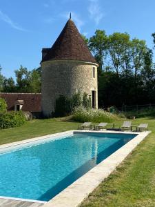 a swimming pool in front of a building with a tower at Tour du manoir de Boiscorde in Rémalard