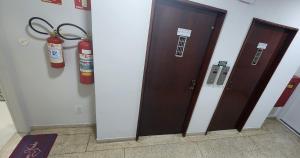 a pair of fire extinguishers on a wall next to two doors at Lindo Apartamento compacto na quadra da praia in Santos