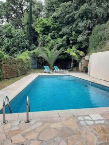 a swimming pool with two blue chairs next to it at Appartement Villa Jardin Piscine in Nice