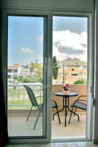 een glazen schuifdeur naar een patio met een tafel en stoelen bij ADONIOS APARTMENTS in Archangelos