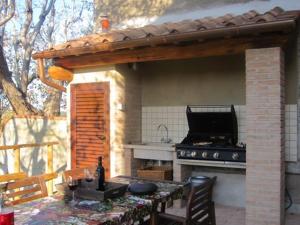 eine Außenküche mit einem Herd und einem Tisch mit Stühlen in der Unterkunft Holiday home Garetto in Chianni