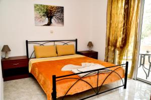 een slaapkamer met een bed met een oranje deken bij ADONIOS APARTMENTS in Archangelos