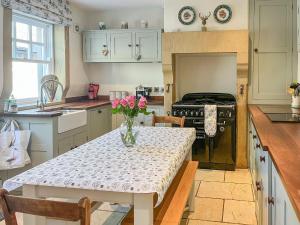 a kitchen with a table with a vase of flowers on it at Puddle Duck Cottage in Bakewell