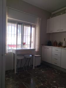 cocina con mesa, 2 taburetes y ventana en Villa Antonia en Chipiona