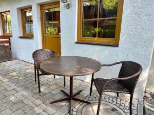 una mesa de madera y 2 sillas en el patio en Ferienwohnungen Hänsel und Gretel - zentral, gemütlich, nah am See, en Schliersee
