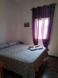a bedroom with a bed with purple curtains and a window at Villa Antonia in Chipiona