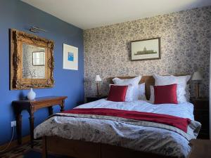 a bedroom with a bed with red pillows and a mirror at Entire Farm House stay, La Gérouardière in Barenton