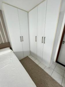 um quarto com armários brancos e uma cama nele em Bilbao Residence no Recife