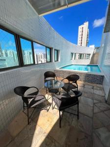 um pátio com cadeiras, uma mesa e uma piscina em Bilbao Residence no Recife