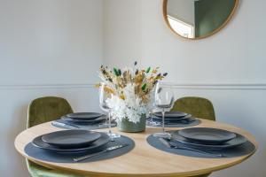 a table with plates and glasses and a vase of flowers at La Petite Plume - PrestiPlace Tours in Tours