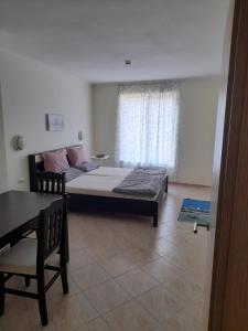 Zimmer mit einem Bett, einem Tisch und einem Fenster in der Unterkunft Negresko Family Apartment in Elenite