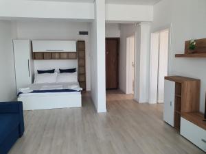 a bedroom with a white bed and a wooden floor at Studio Alex in Năvodari +5 photos