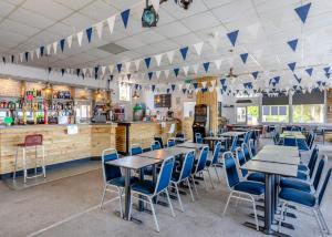 a restaurant with tables and chairs and a bar at Brixham Holiday Park in Brixham