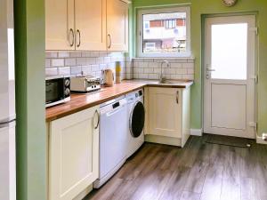 a kitchen with white cabinets and a washer and dryer at Castle Park in Ceres