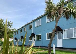 a blue building with a palm tree in front of it at Brixham Holiday Park in Brixham