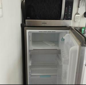 einen Kühlschrank mit offener Tür und eine Mikrowelle in der Unterkunft Alabang Staycation in Manila